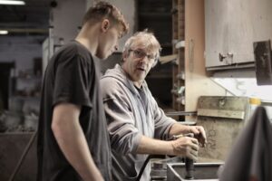 Experience male engineer sharing knowledge with male apprentice