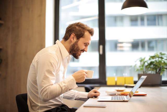 Office worker looking at laptop with a coffee